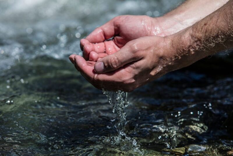 Hands sachibalaya clean water from the mountain stream bubbling